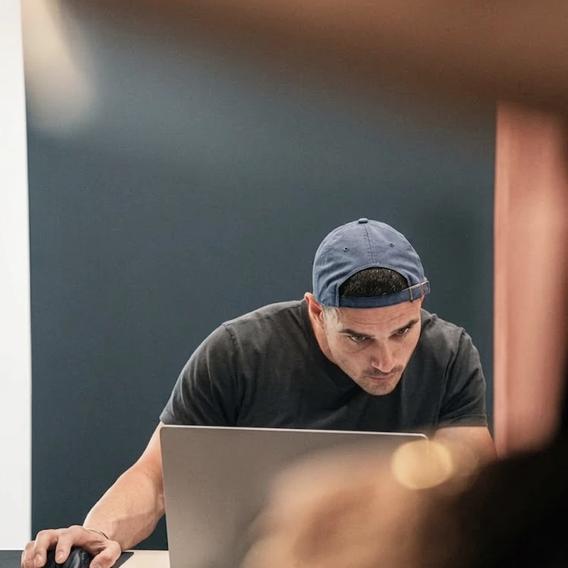 Developer with cap working on laptop