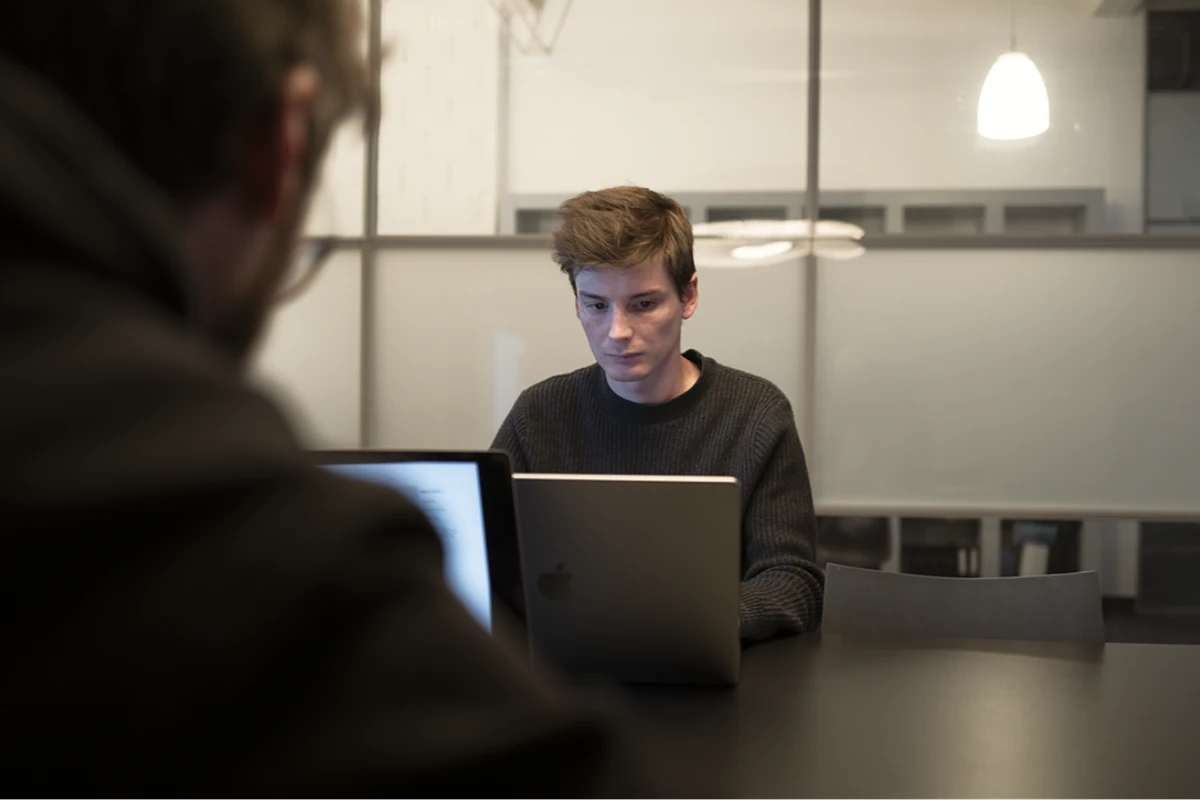 Person focused at laptop in dark workspace